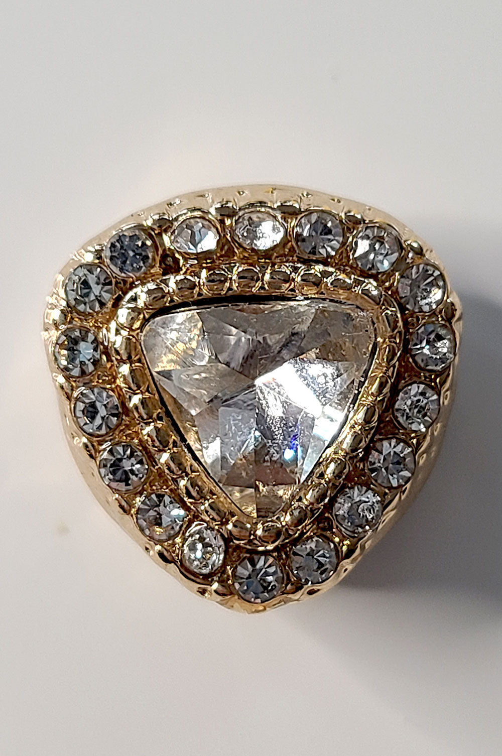 Gold triangle with a large central diamond and smaller diamonds around on a light background